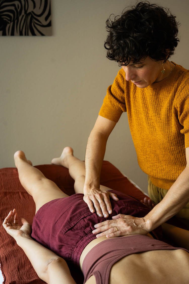 La Fasciathérapeute Laurence Stenzin fait de la thérapie manuel sur le bassin et la colone, d'une patiente qui est allongé sur une table de massage