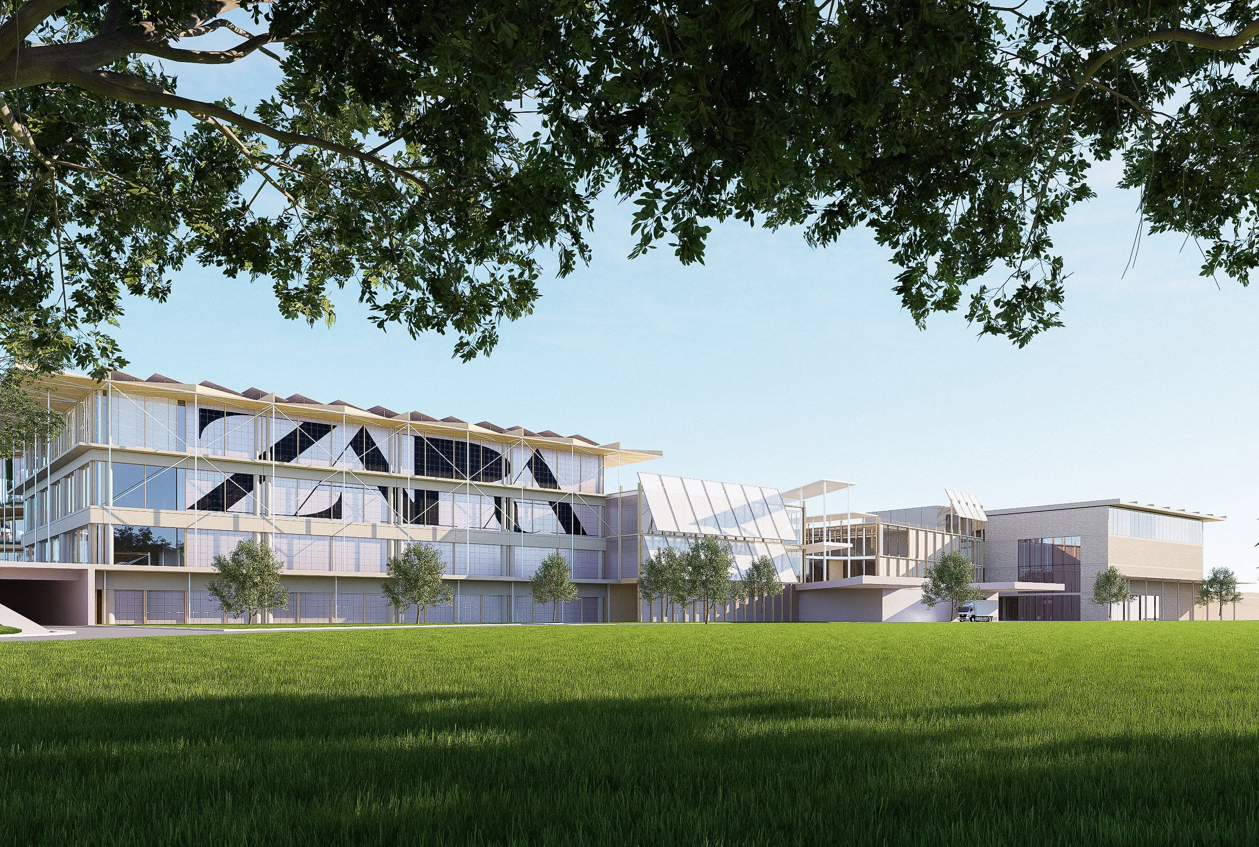 Edificio moderno con estructura de vidrio y paredes blancas, rodeado de césped verde y árboles, bajo un cielo despejado.