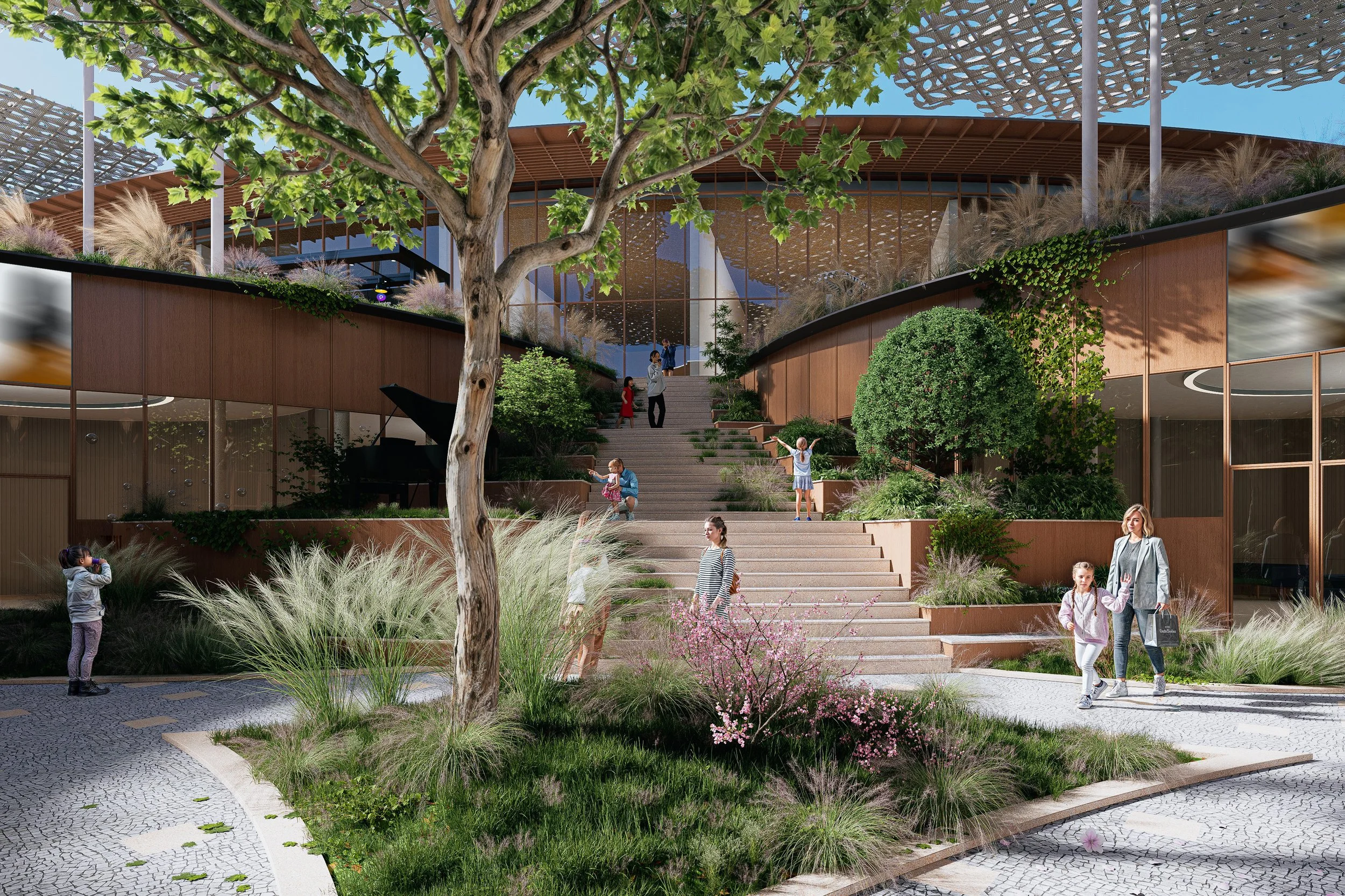 Escalera de acceso a un edificio moderno con áreas verdes y árboles, varias personas, niños y adultos, caminando y disfrutando del espacio exterior con plantas y flores.