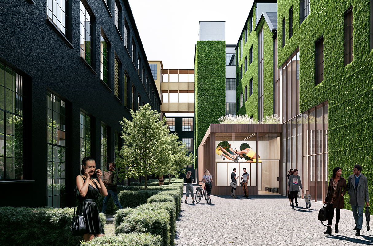 Vista de un patio urbano con edificios de paredes verdes y ventanas grandes, personas caminando, una de ellas con un ciclista, y un cartel que muestra arquitectura moderna.