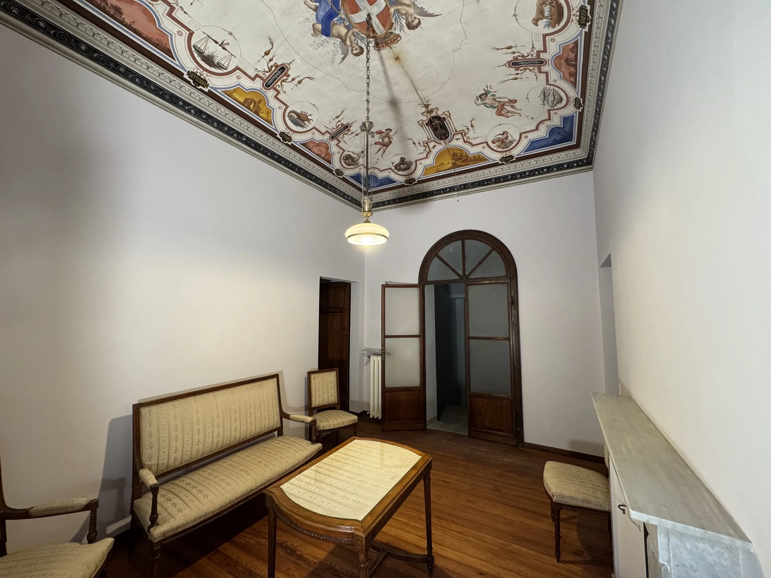 Stanza con soffitto decorato con affreschi, arredi classici e pavimento in legno