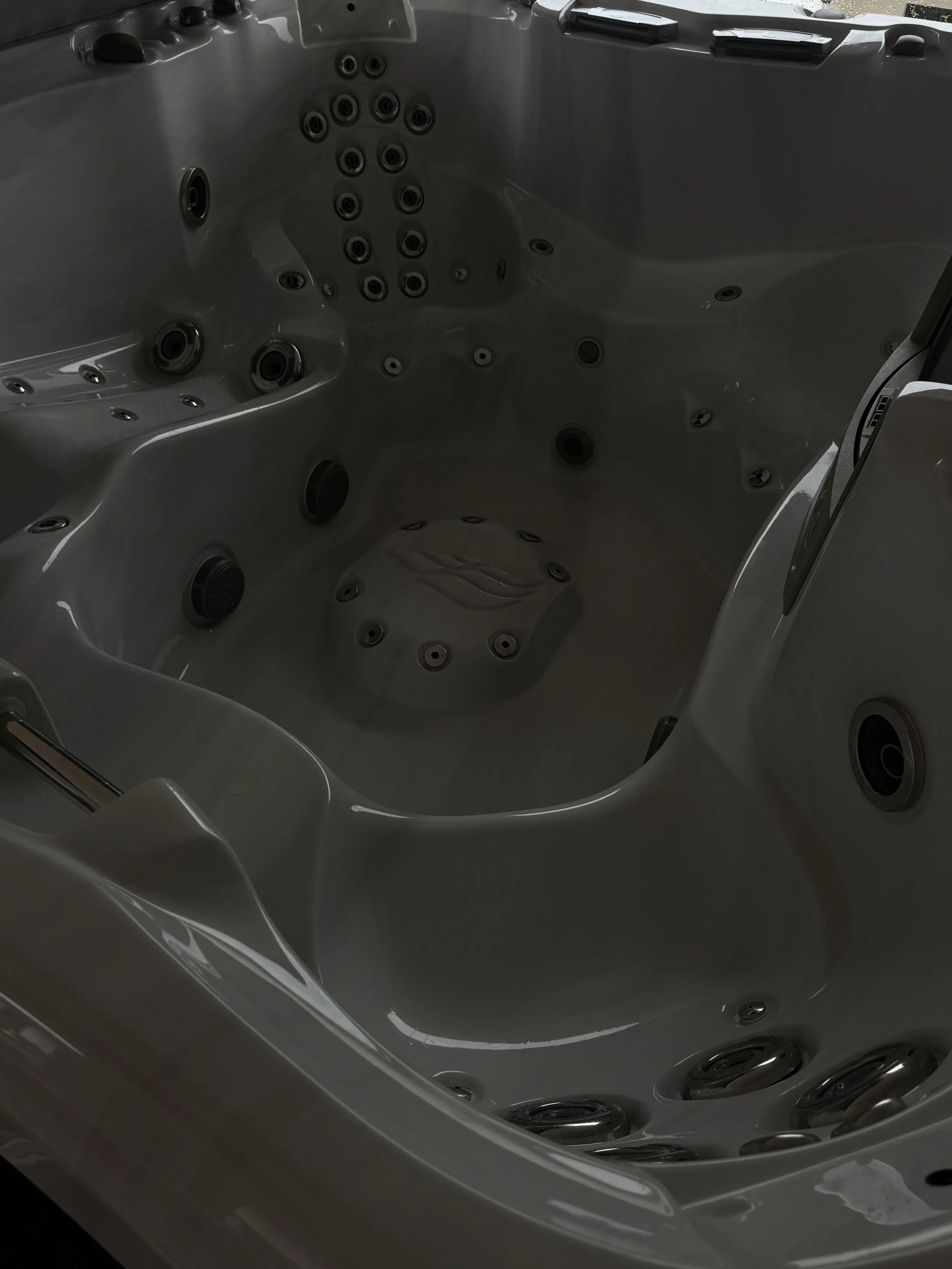 Empty hot tub with multiple jets and seating areas.