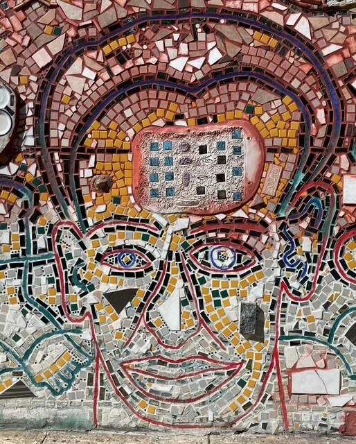 Colorful mosaic mural of a smiling person's face with exaggerated features and vibrant patterns.