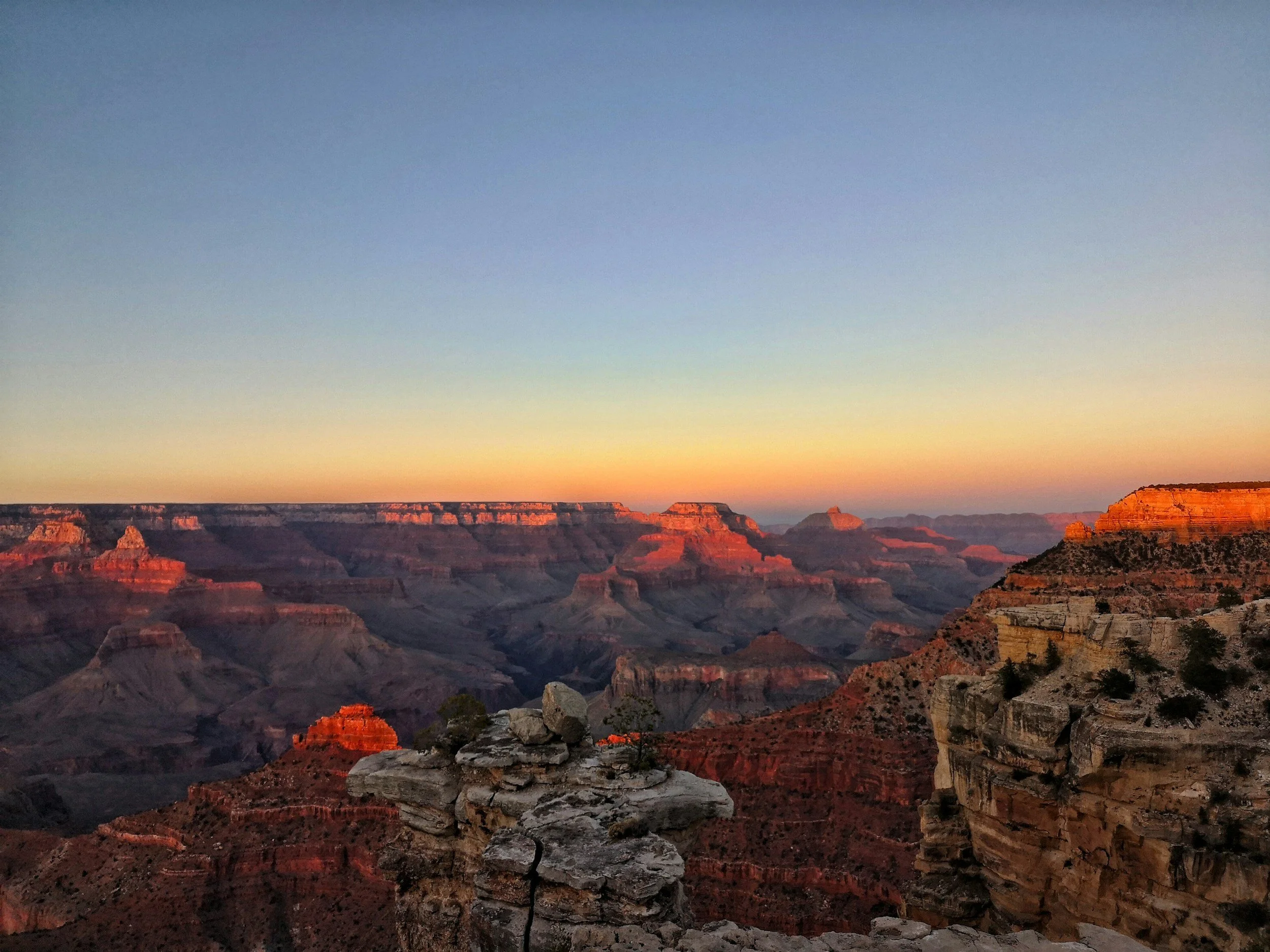 Sunset view of the Grand Canyon with layered rock formations and a clear sky.