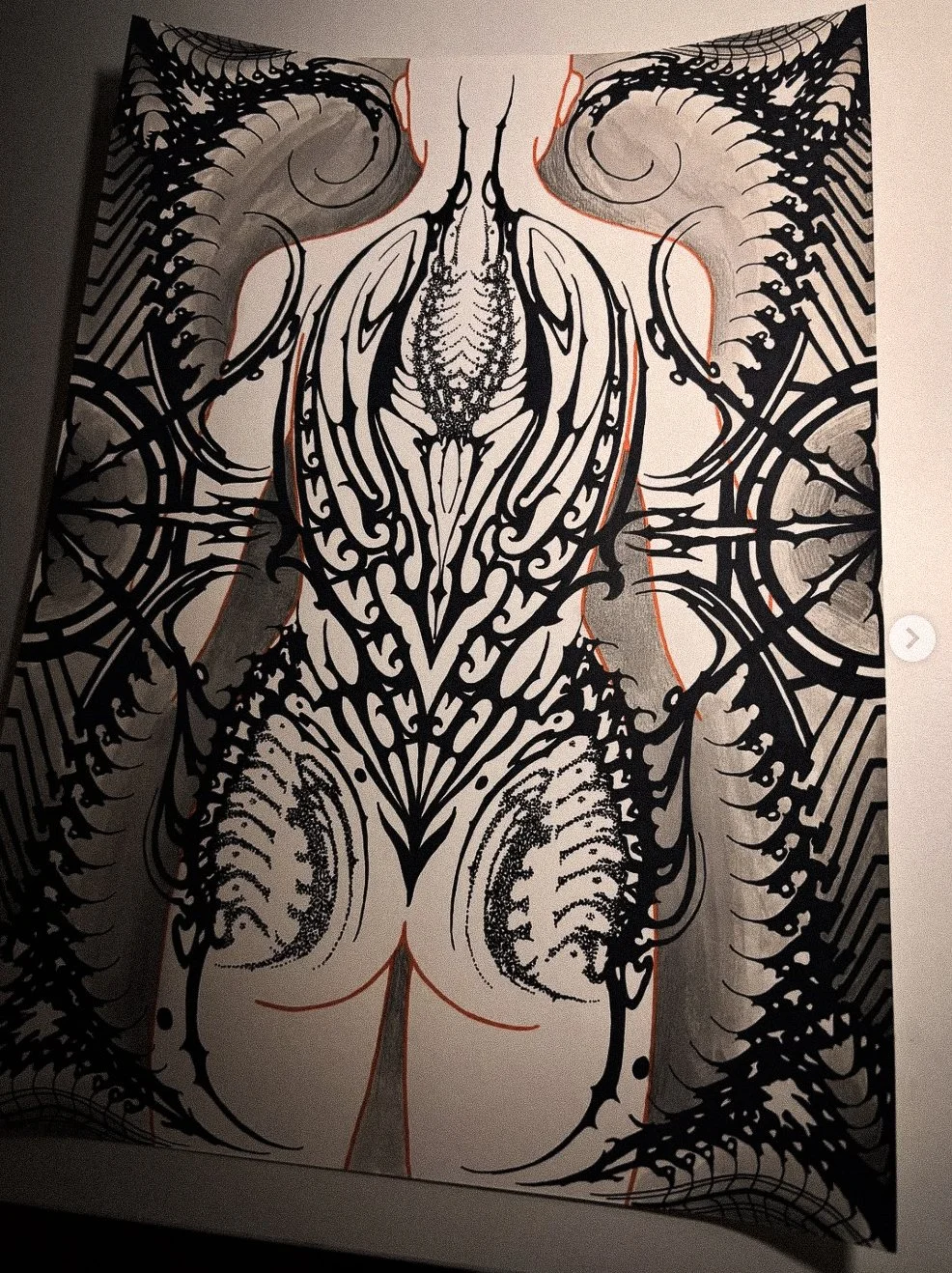 A black and white tattoo design of a stylized insect or alien creature, intricate with swirling patterns and lines, covering the entire back and shoulders.