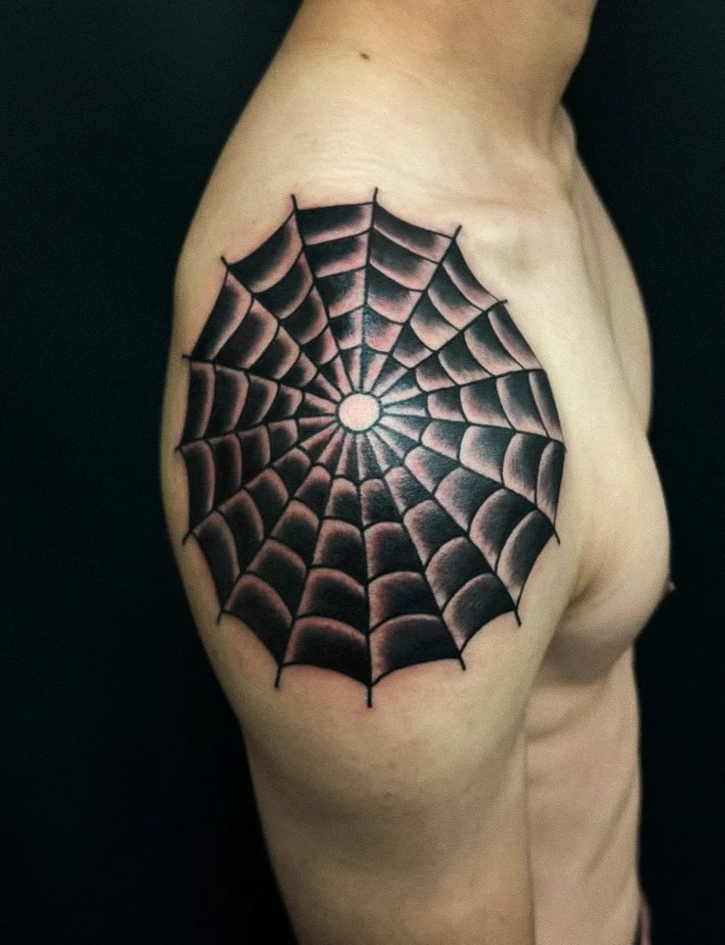 Tattoo of a spider web on a person's shoulder.