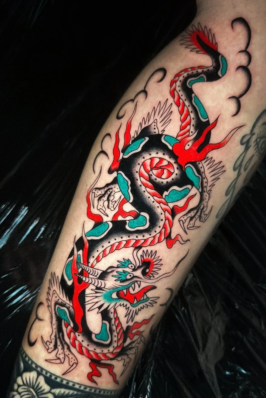 Traditional Japanese style tattoo of a dragon with black, red, teal, and white colors, surrounded by stylized clouds.