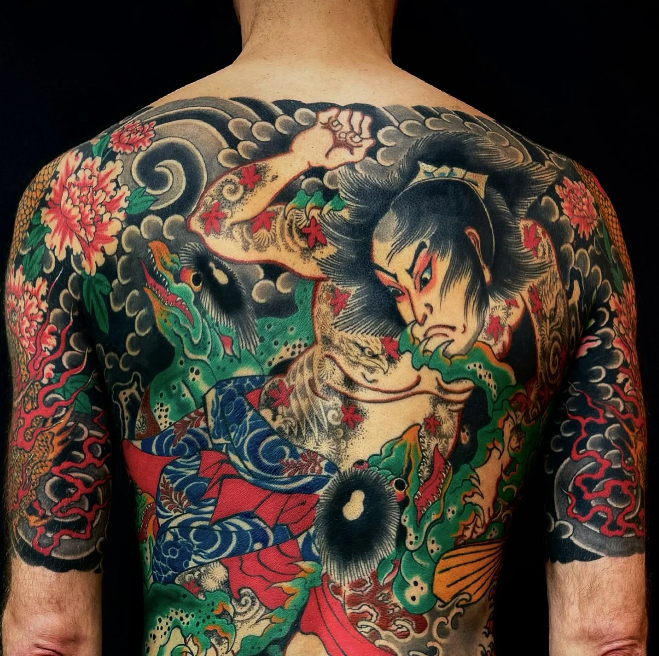 A person's back and arms heavily tattooed with traditional Japanese Irezumi style, featuring a fierce warrior, a dragon, and floral patterns.