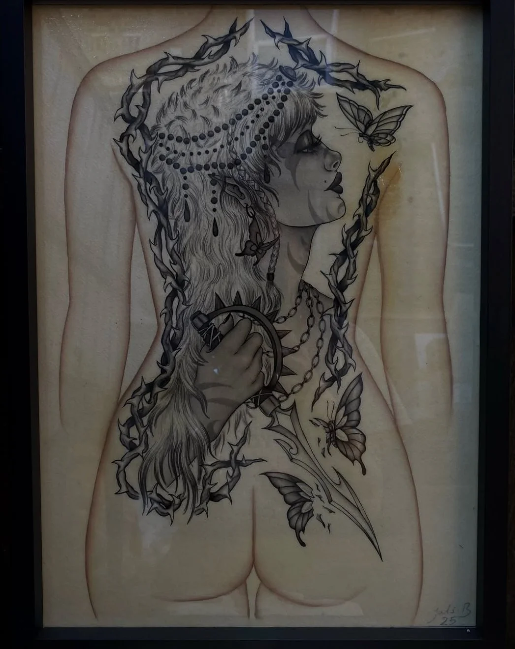 Tattooed woman with long hair, surrounded by butterflies and chains, holding a dagger, with a butterfly on her face, depicted on a nude human back.