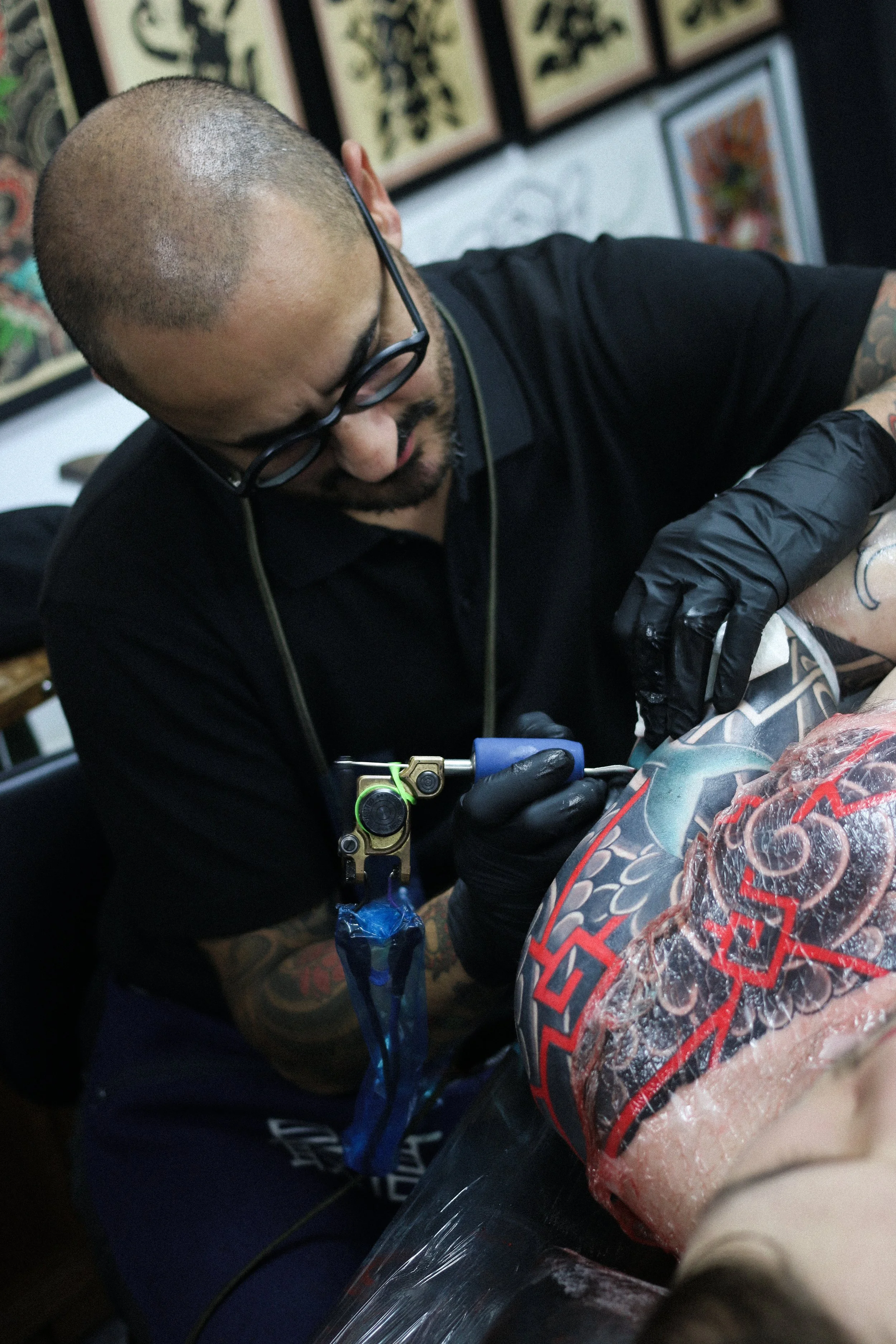 Tattoo artist tattooing a person's calf in a tattoo studio.