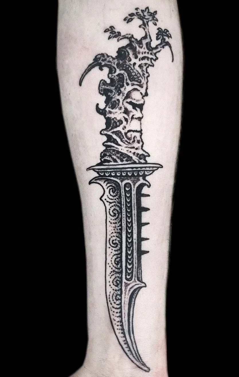 Tattoo of a sword with an intricate design, topped with a tree growing from the hilt, on a person's forearm.