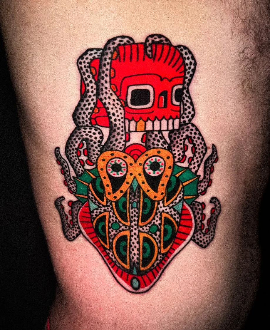 Colorful tattoo of a sugar skull with octopus tentacles on top and a heart-shaped design at the bottom.