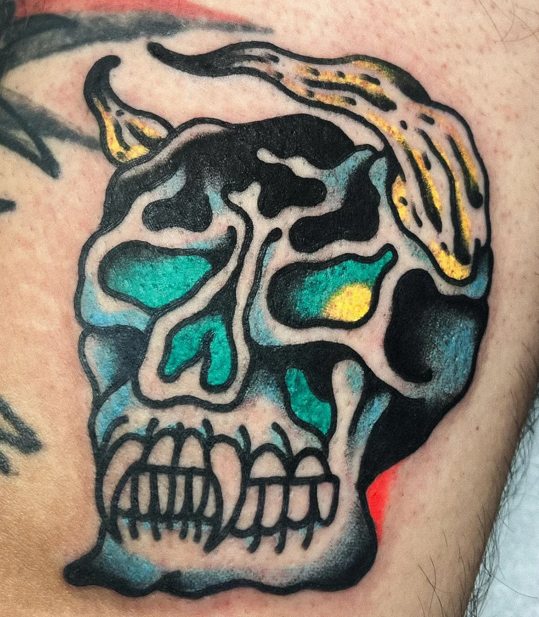 Colorful tattoo of a skull with abstract and vibrant patterns on skin.
