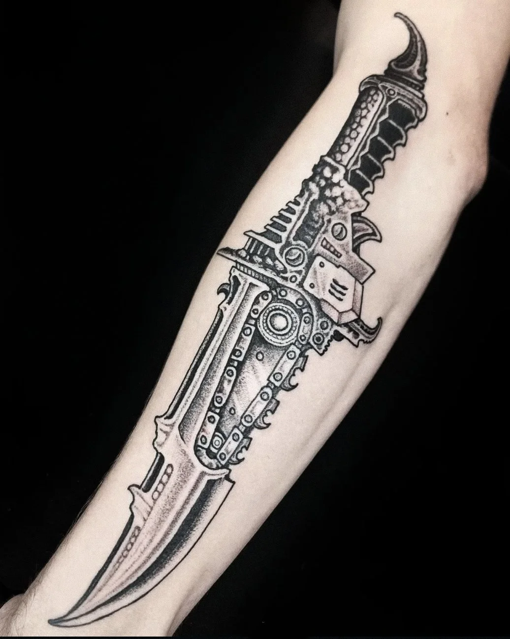 Tattoo of a detailed, mechanical knife on person's arm.