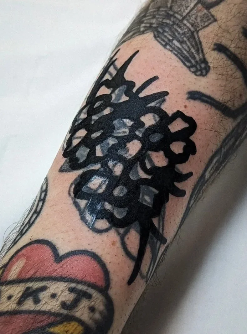 Floral black blastover coverup tattoo on a person's forearm.