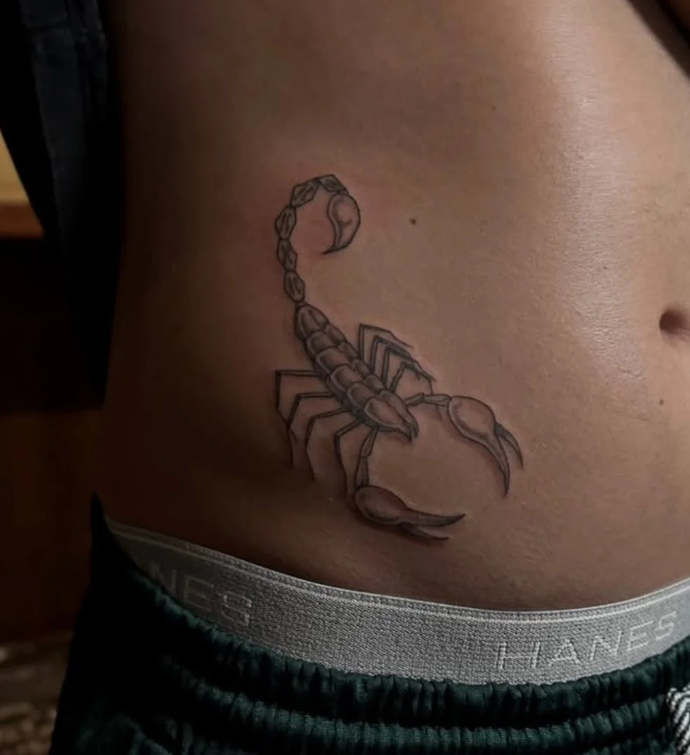 Tattoo of a scorpion on a person's side.