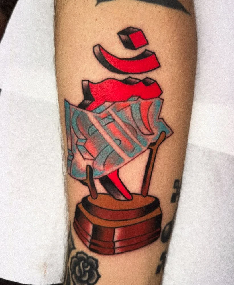 Tattoo of a jukebox with stylized, colorful design and bold black outlines on someone's arm.