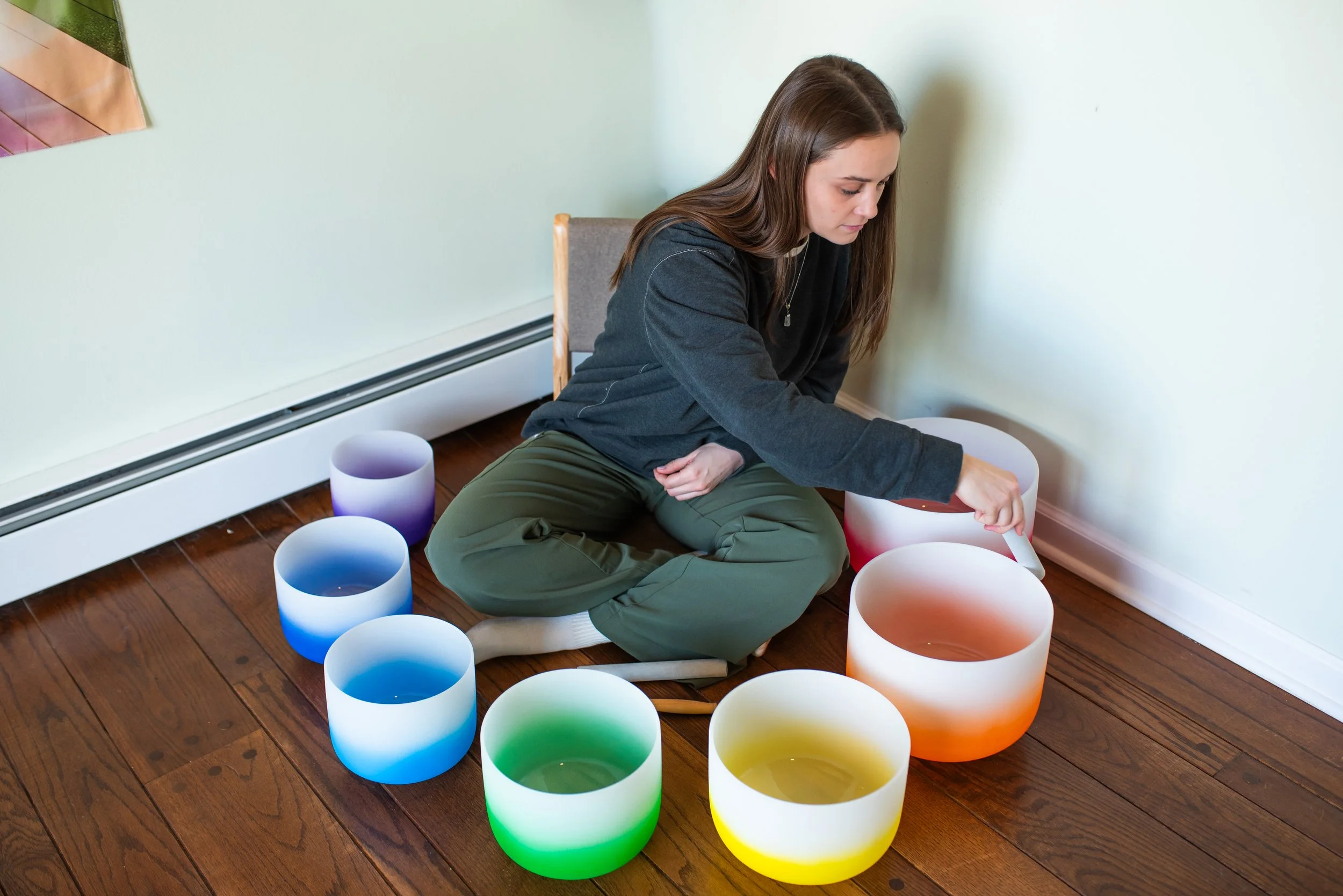 Holistic therapist playing crystal sound bowls to align the body and chakras, providing deep relaxation