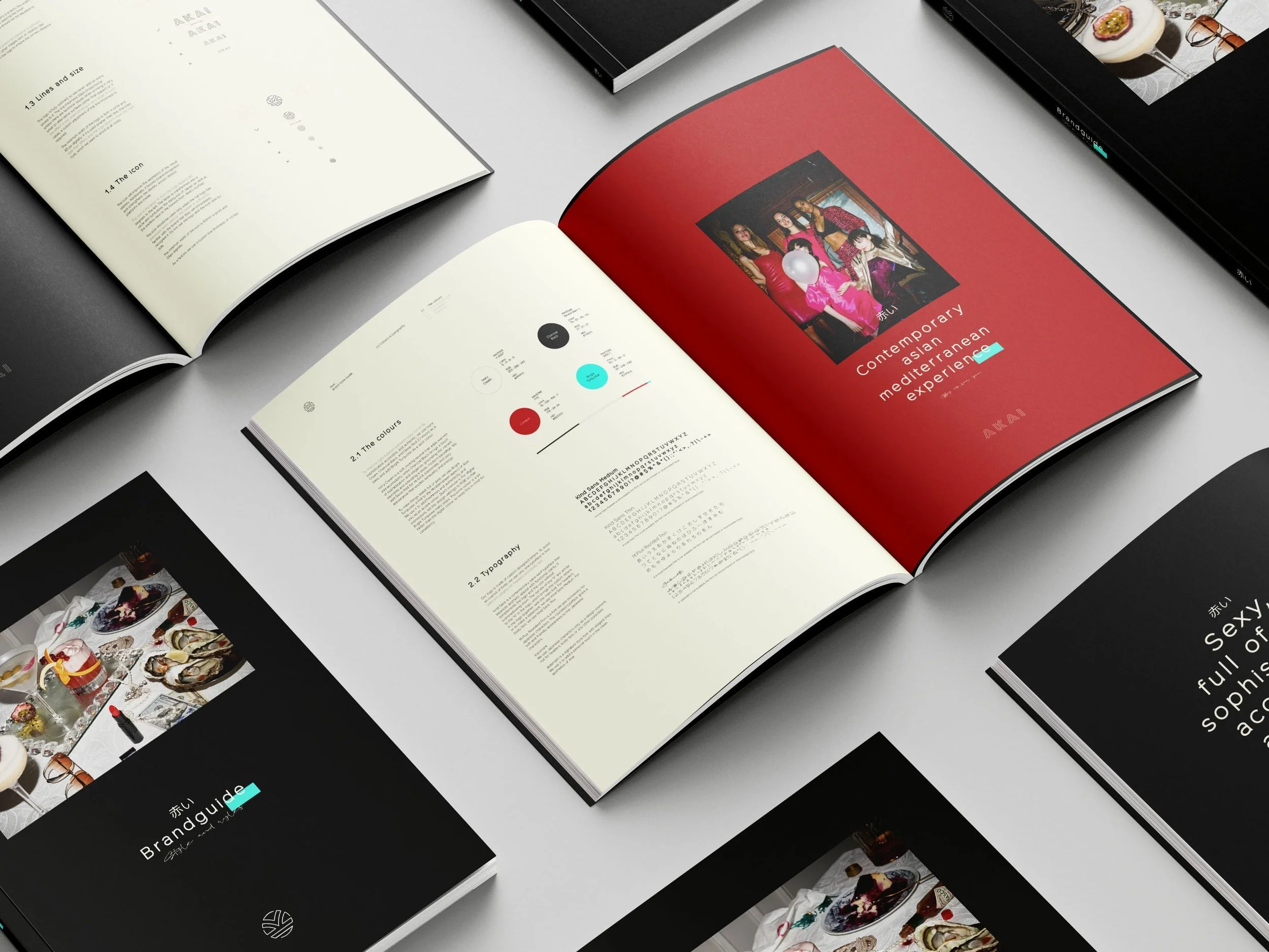 Open magazines on a table displaying design and branding content, with some pages showing images, color palettes, and text. The prominent magazine has a red page with a photo of a group of women and the text "Contemporary Asian Mediterranean experience."