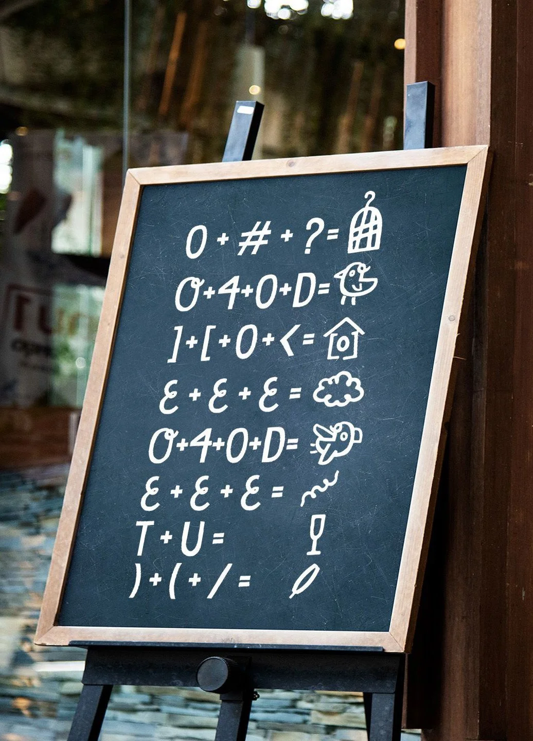 Chalkboard with various symbols, numbers, and illustrations including a house, duck, cloud, rabbit, and wine glass.