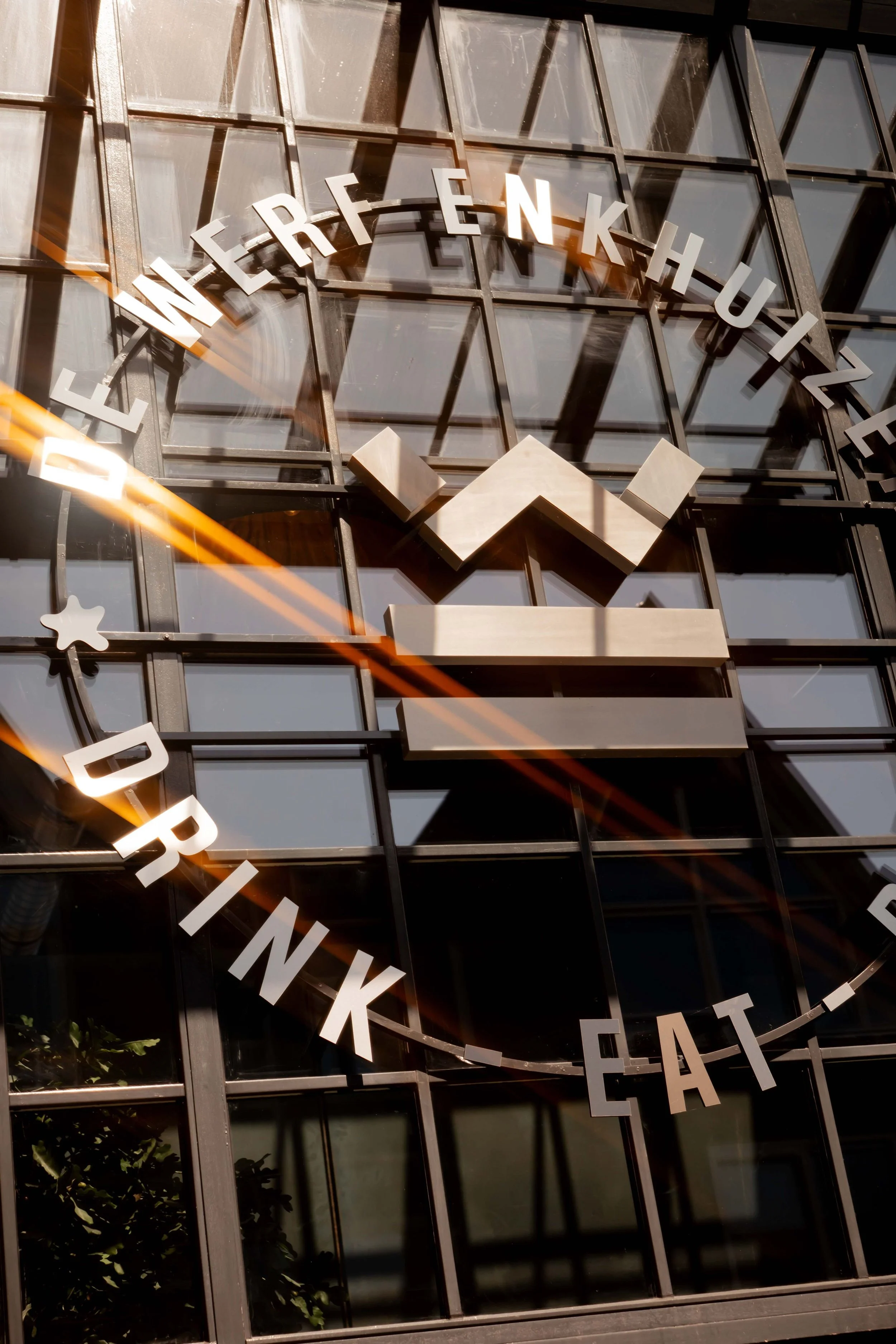 Clock with the words 'EAT DRINK ENJOY' circling around and the University of Washington Husky logo in the center on a glass building.