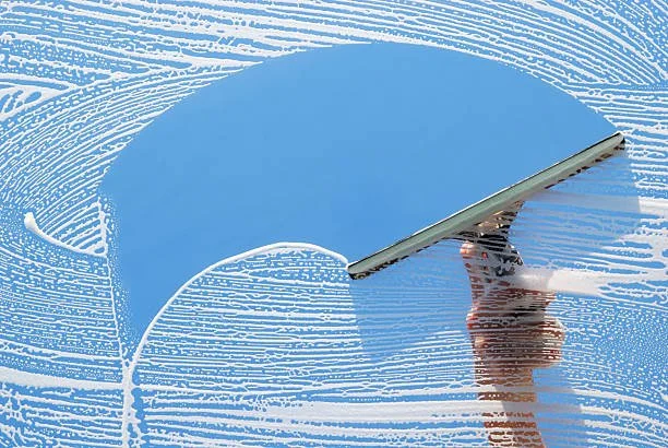 Person cleaning a glass window with a squeegee
