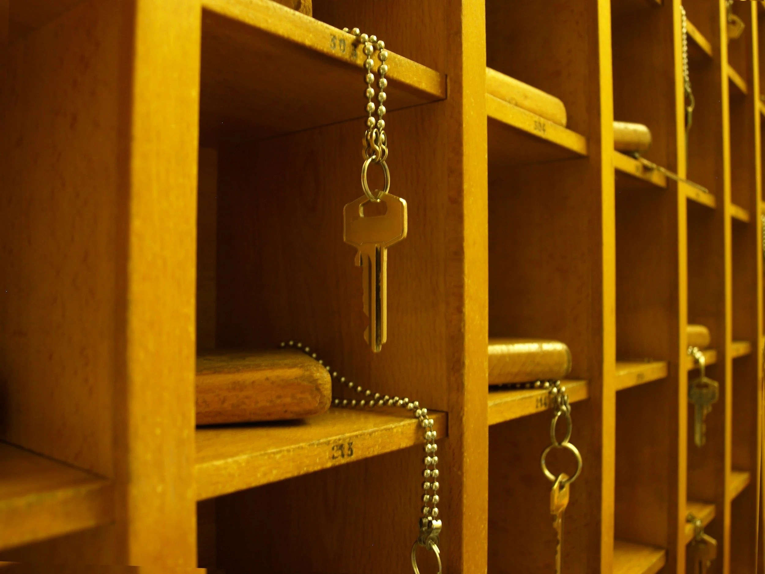 A wooden mail locker with key strings hanging from some compartments.