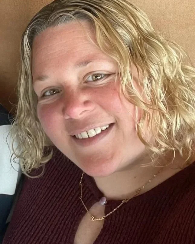 A woman with blonde, curly hair smiling at the camera.