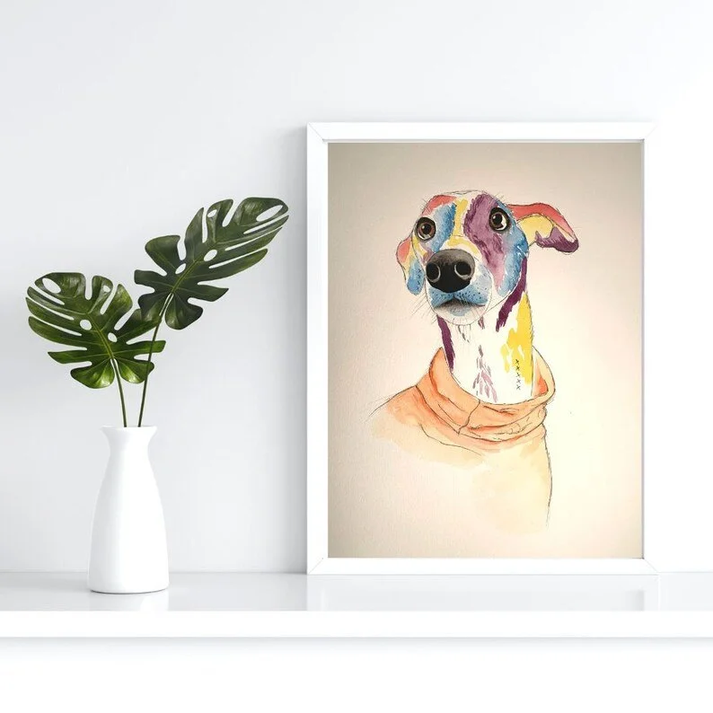 Colorful illustration of a dog in a white frame, placed on a white surface next to a white vase with green monstera leaves.
