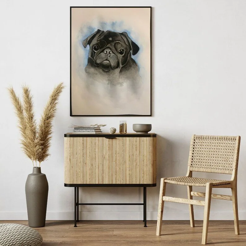 Living room with a modern wooden sideboard, a wicker chair, a tall vase with pampas grass, and a large framed painting of a cute pug dog on the wall.