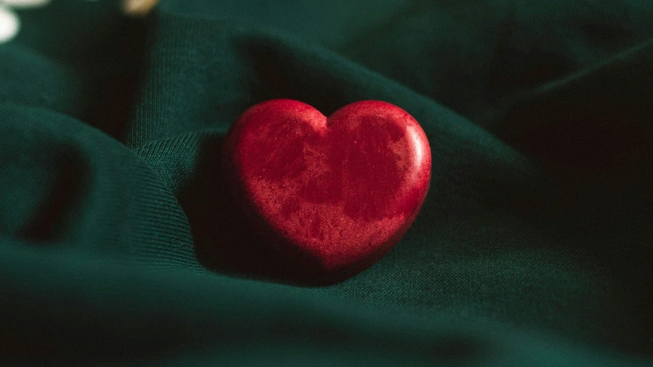 A red heart-shaped stone on dark green fabric.
