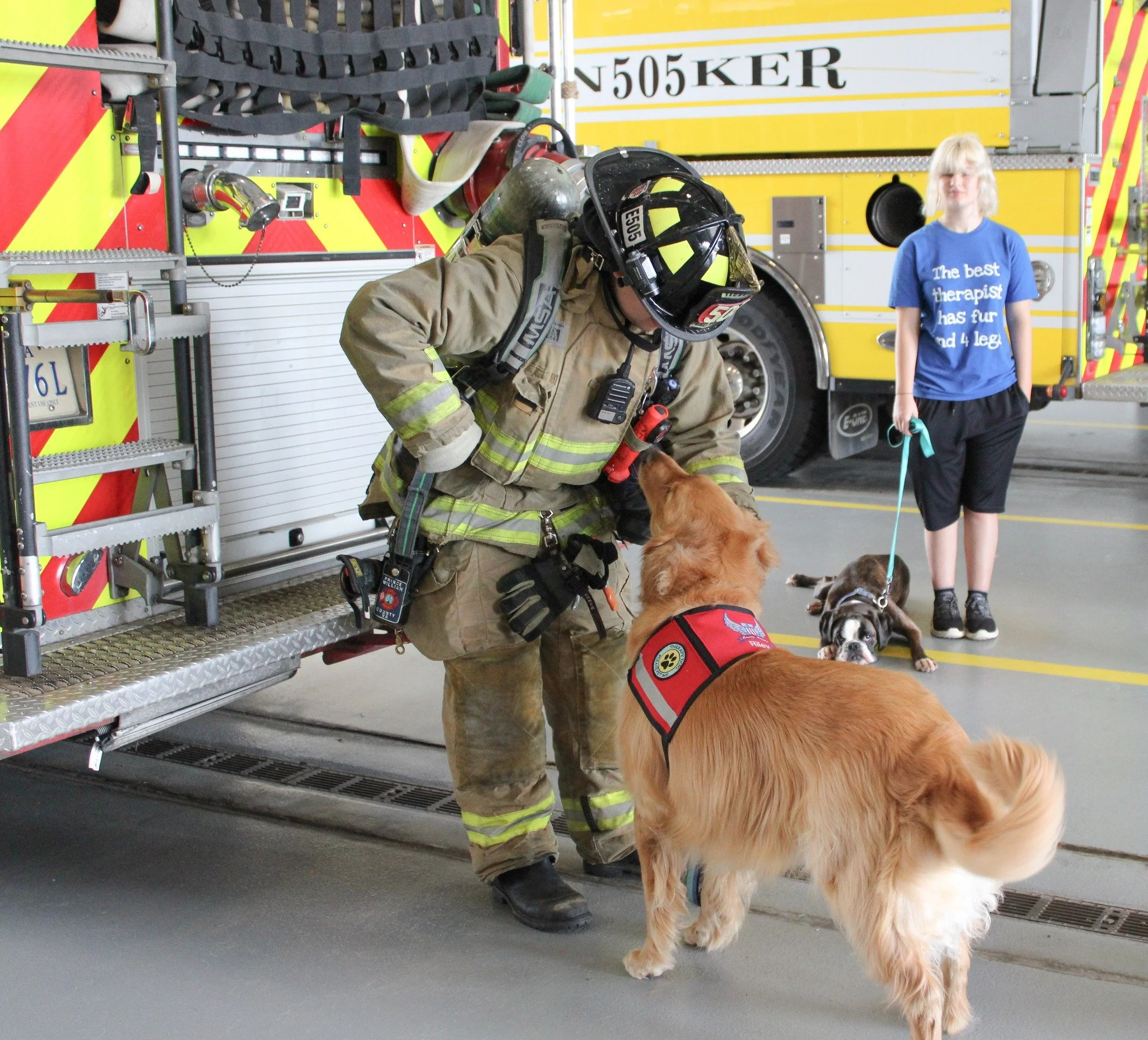 Firefighter with a service dog and a woman with a dog in a fire station