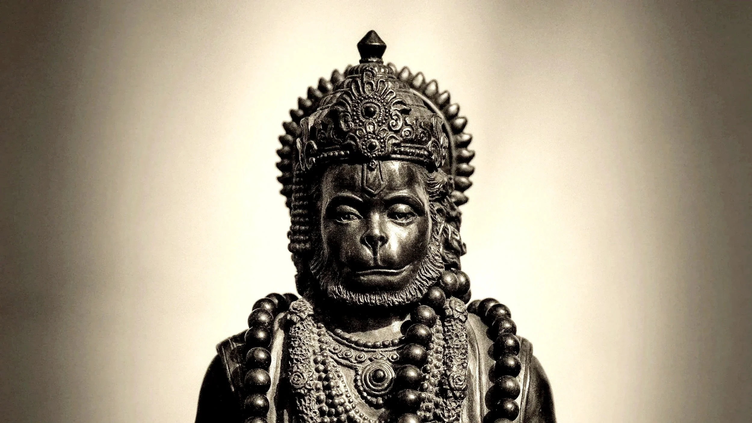 A statue of a regal figure wearing an ornate crown and jewelry, with a serious expression.