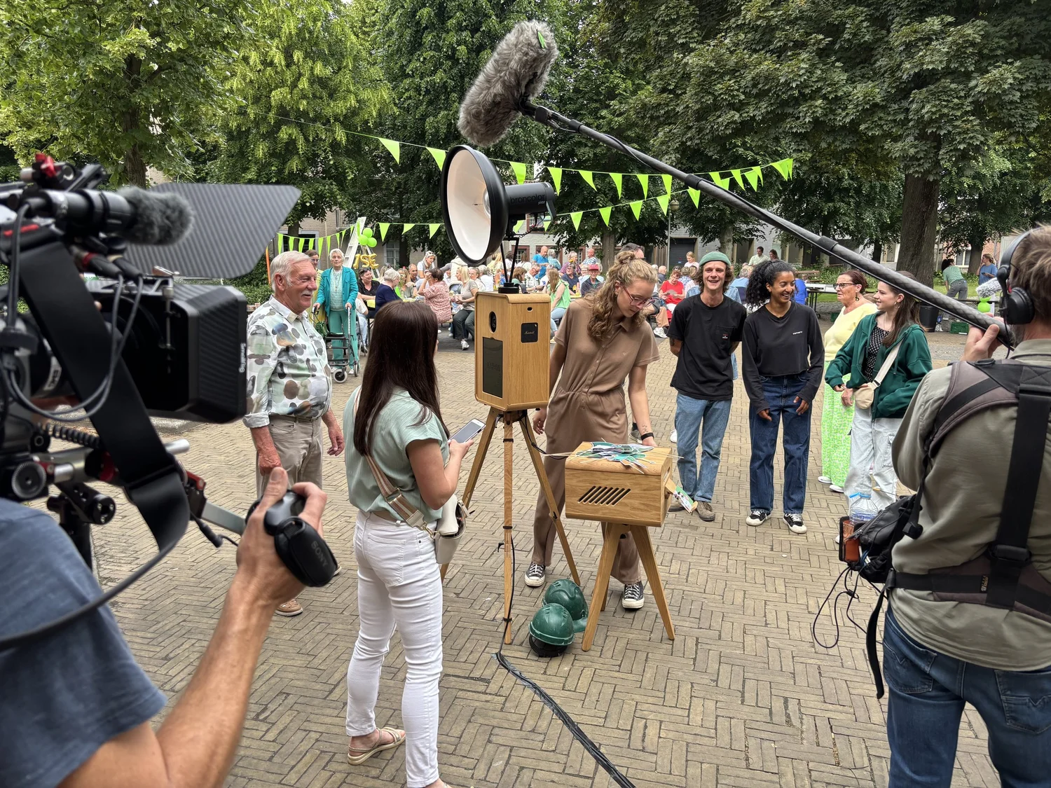 Een cameraploeg van Huis Gemaakt filmt gasten aan de photobooth van Maison Dardenne op een buurtfeest