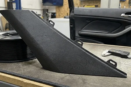 Car interior part on a workbench in a garage 3d printed using ASA and ABS filament.