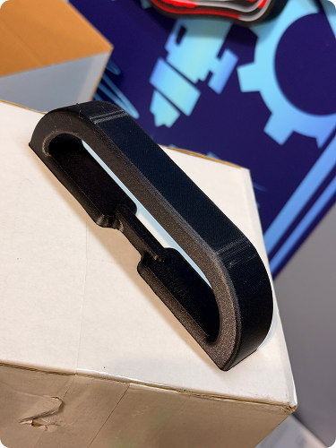 A black plastic and foam object with a U-shaped slit placed on top of a cardboard box.