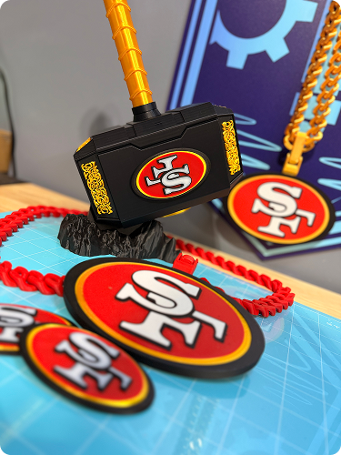 San Francisco 49ers themed merchandise, including patches and a toy hammer with the 49ers logo, on a table with a blue background.