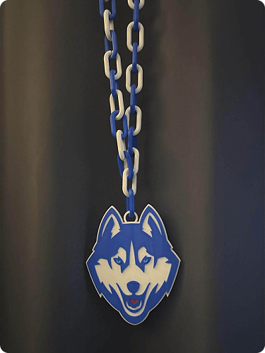 A chain with blue and white links hanging from the ceiling, with a husky mascot pendant attached, against a dark background.