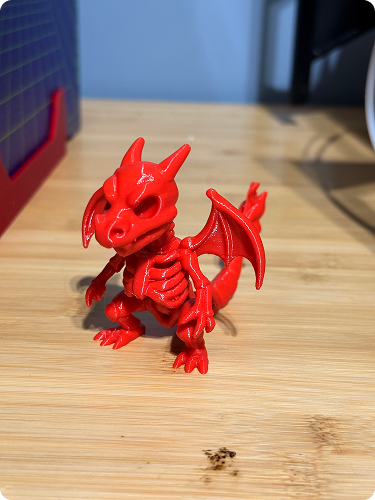 Red dragon figurine with detailed wings and horns on a wooden surface.