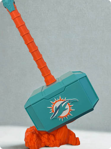 A toy hammer with a teal head featuring the Miami Dolphins logo and an orange handle, resting on an orange base.