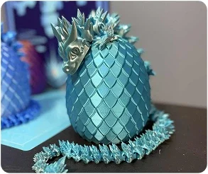 Decorative pineapple-shaped object with a blue textured surface and a spiky gold top, surrounded by a blue tinsel garland.