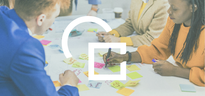 People working on a brainstorming session at a table with sticky notes and pens.