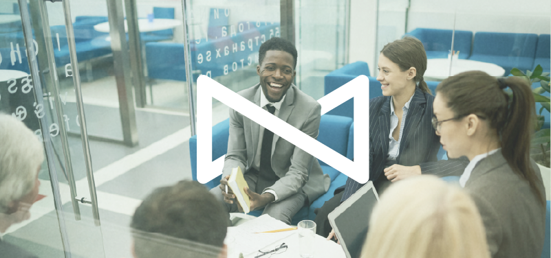 Coaching: Moving from Fear to Clear Action [Group of professionals having a meeting in a modern office, with one man smiling and holding a notebook.]