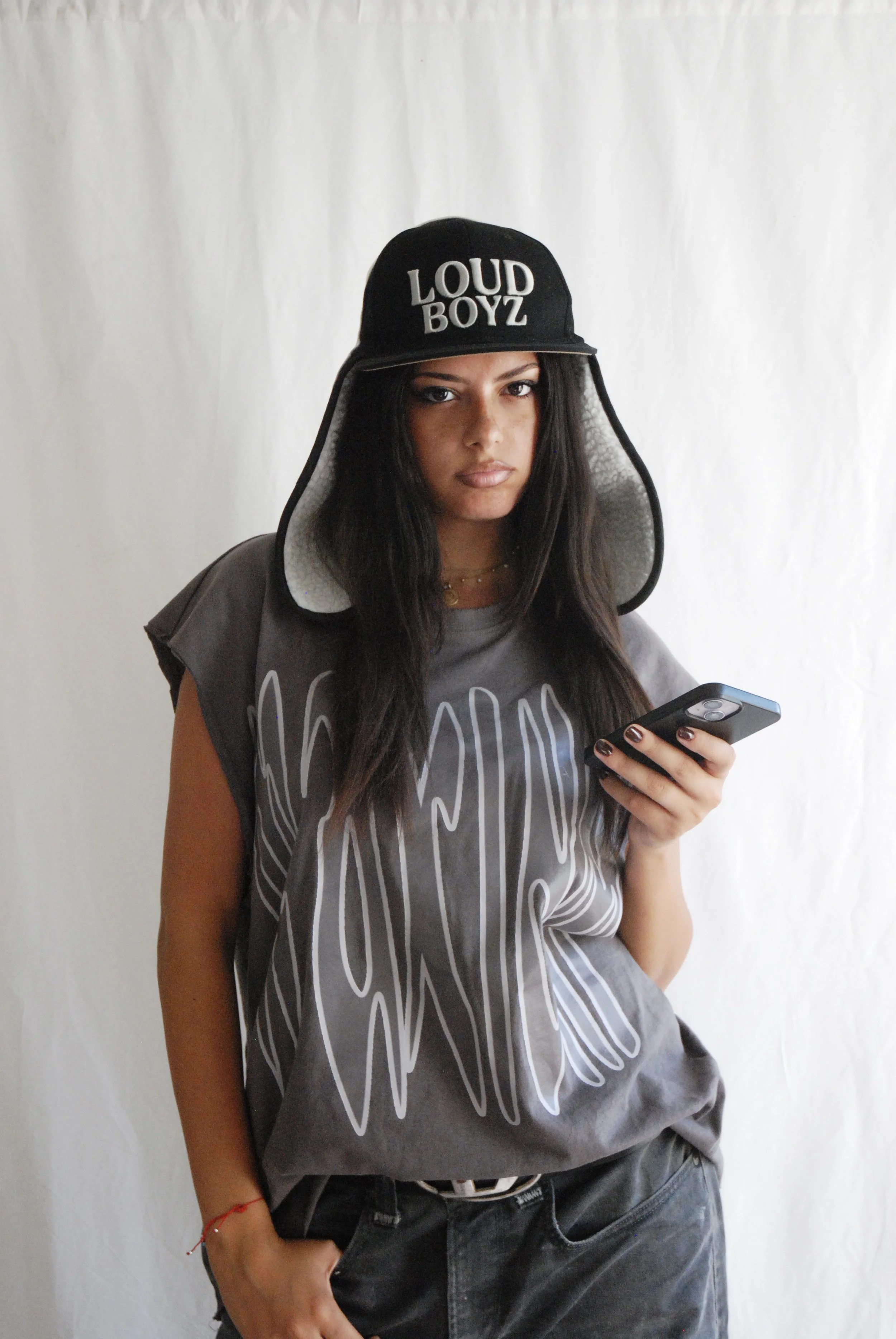 Une jeune femme en tenue décontractée, portant un casque sur lequel est inscrit « LOUD BOYZ », regarde son téléphone.