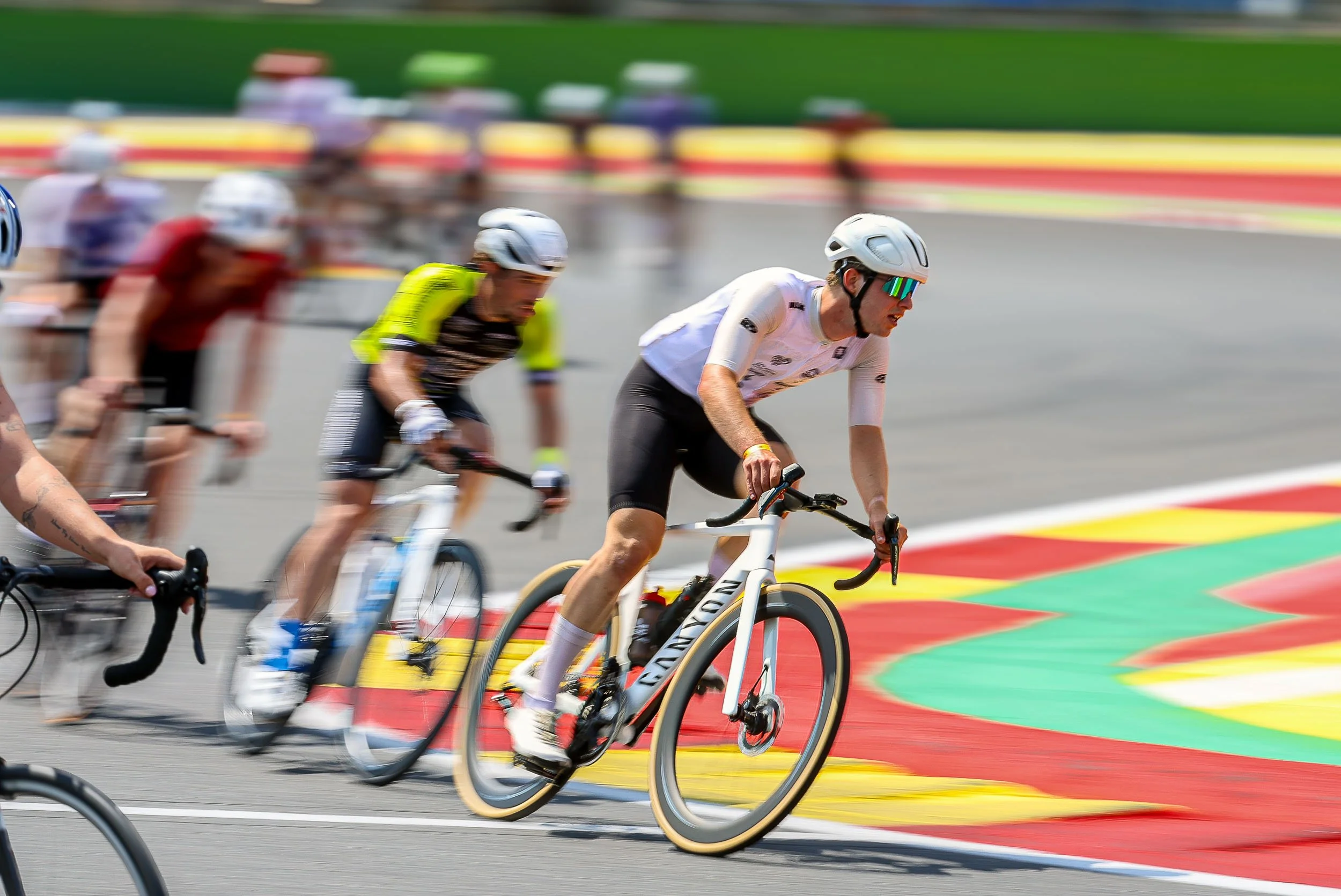 Cyclists racing on a car track with colorful markings.