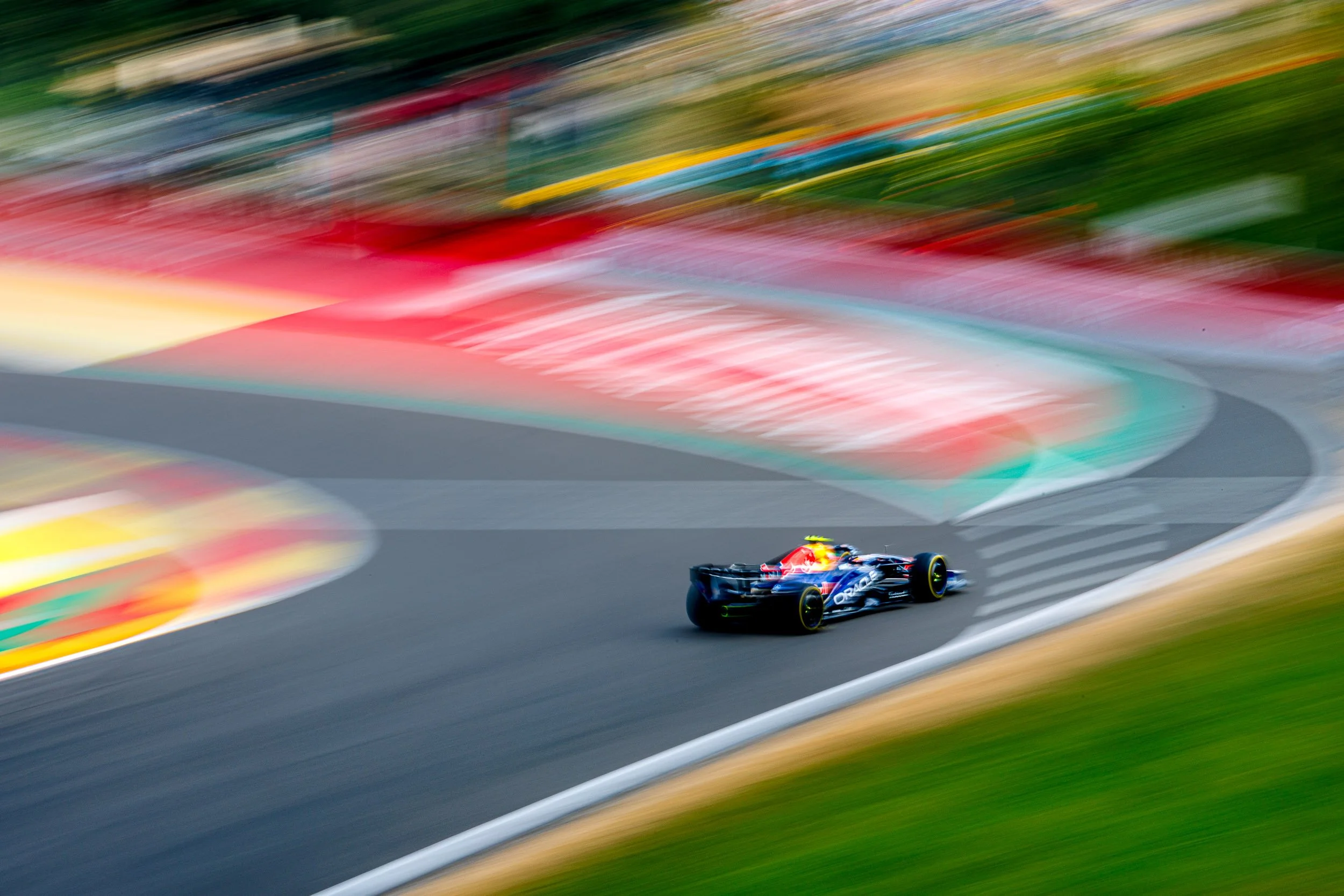 A Formula 1 race car on a race track, with motion blur and colorful track barriers in the background.