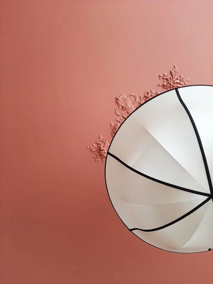 Un plafond terracotta avec une lampe blanche ronde en soie et plafond moulures.