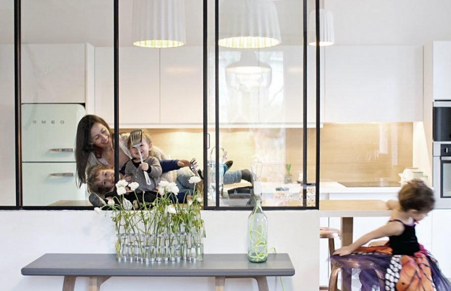 Famille dans cuisine design - travers la verrière maison Smala Sceaux · design résidentiel Mélanie Trinkwell
