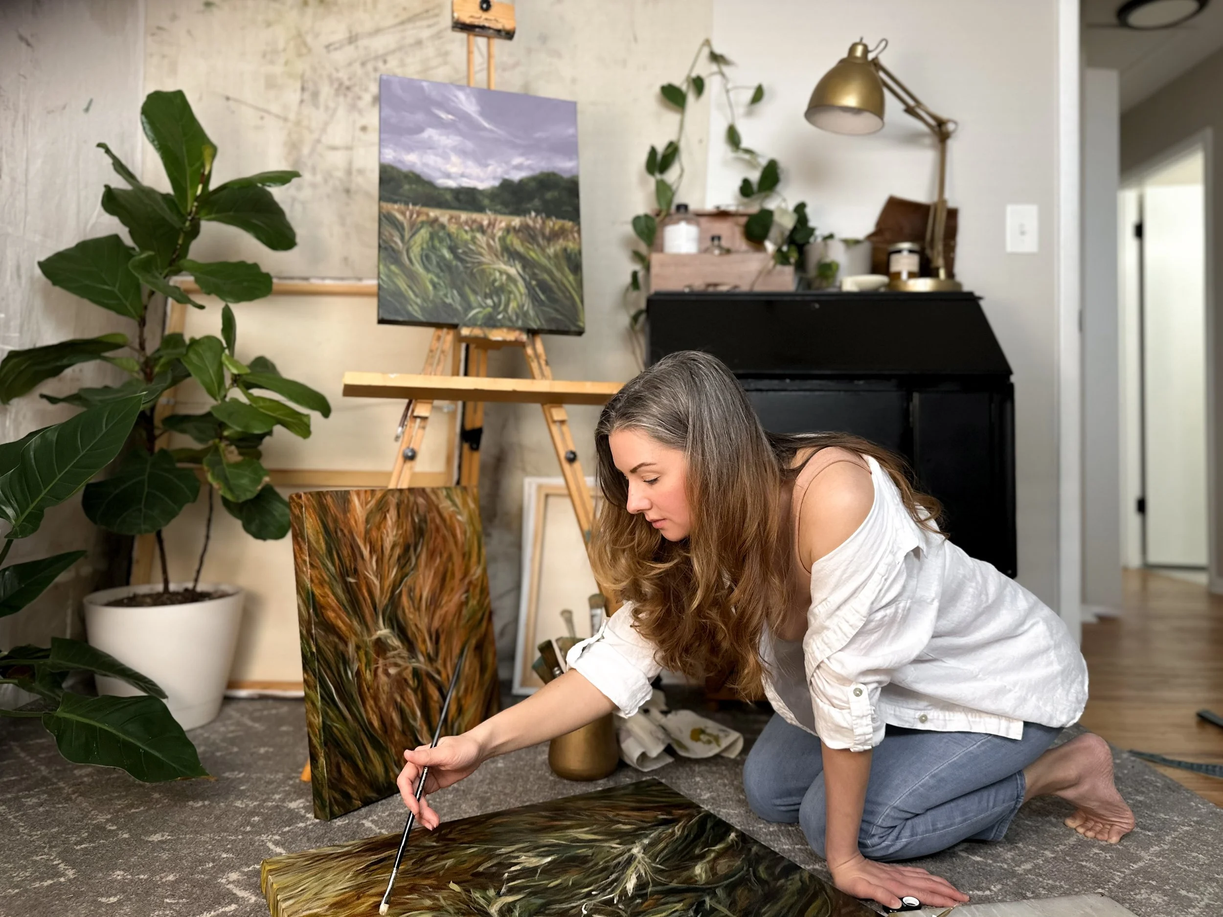 A woman with long hair standing at an open window of a brick building, looking outside.