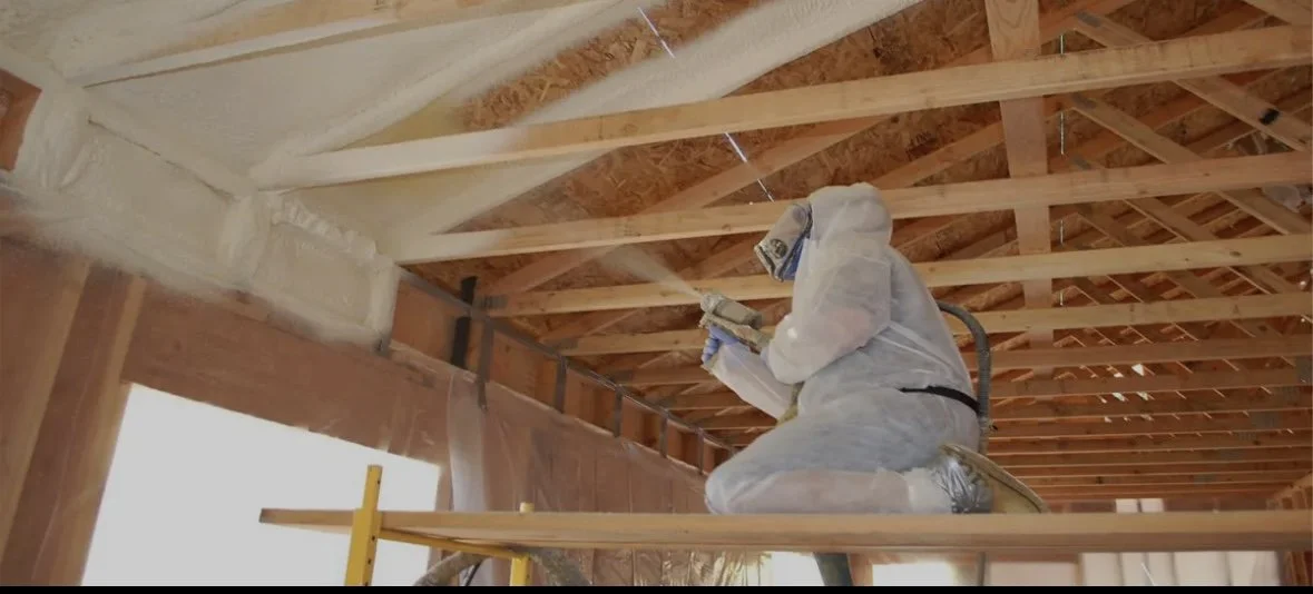 Construction worker installing insulation in the ceiling of a building under construction.